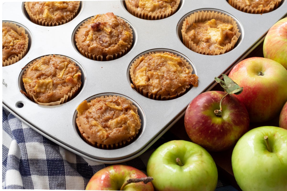 Apple Pecan Quinoa Muffins in a muffin tin with fresh apples on the side