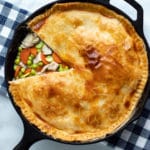 Easy low carb chicken pot pie baked in a cast iron skillet with a wedge cut from the top crust so you can see the filling of chicken peas and carrots and gravy