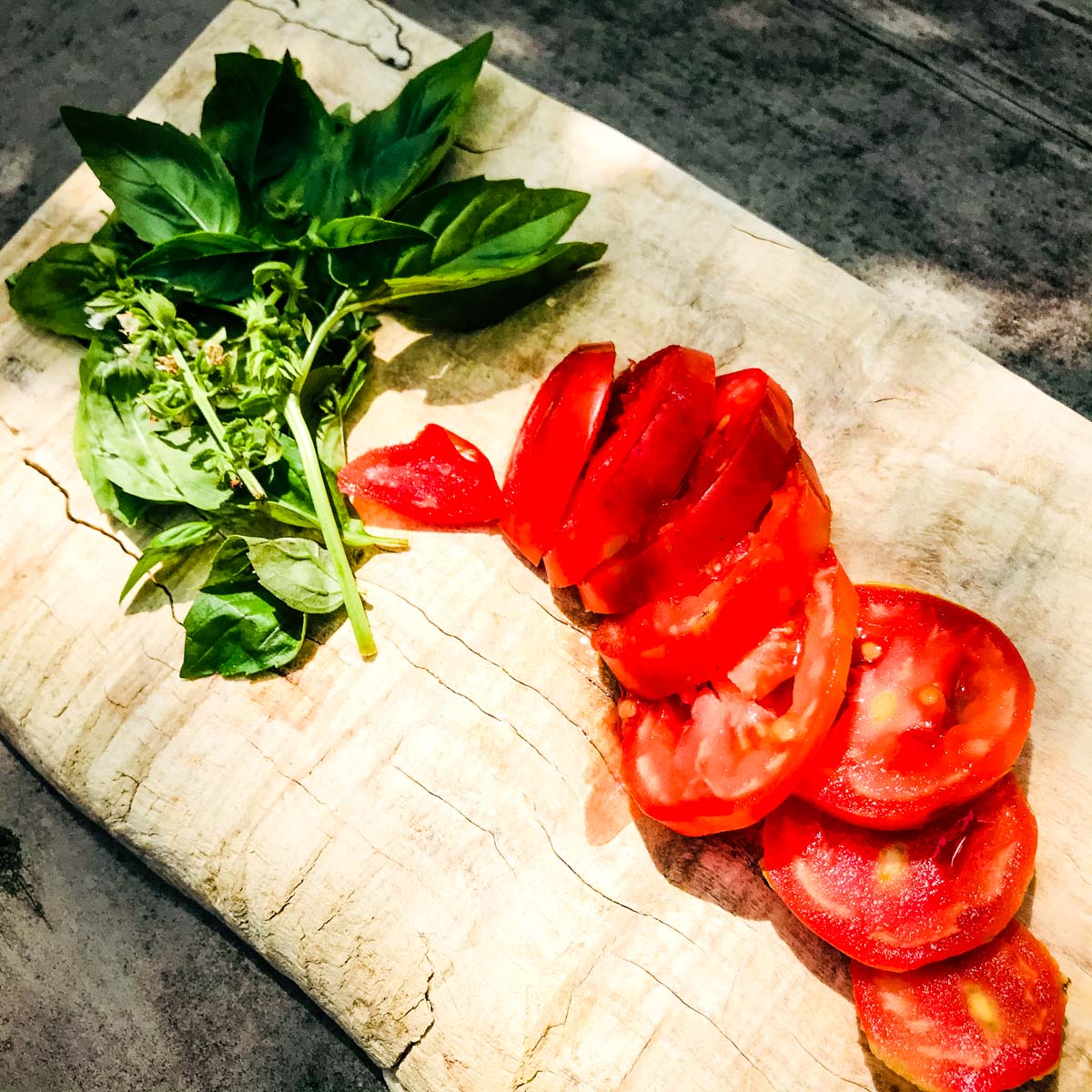 basil and sliced tomatoes on a cutting board