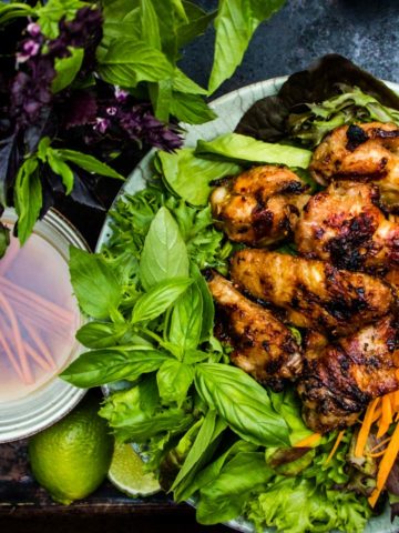 over head view of Grilled lemongrass chicken wings with basil lettuce shredded carrots cucumber and dipping sauce