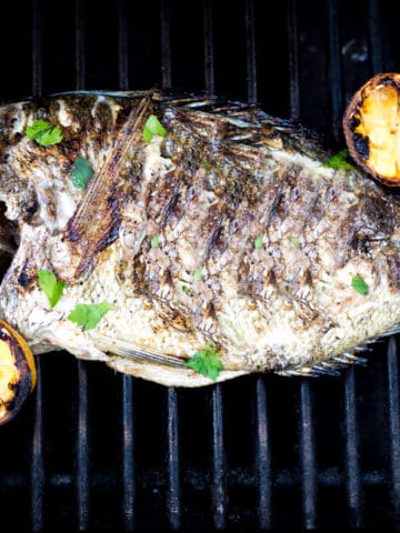 whole fish on the grill with lemons
