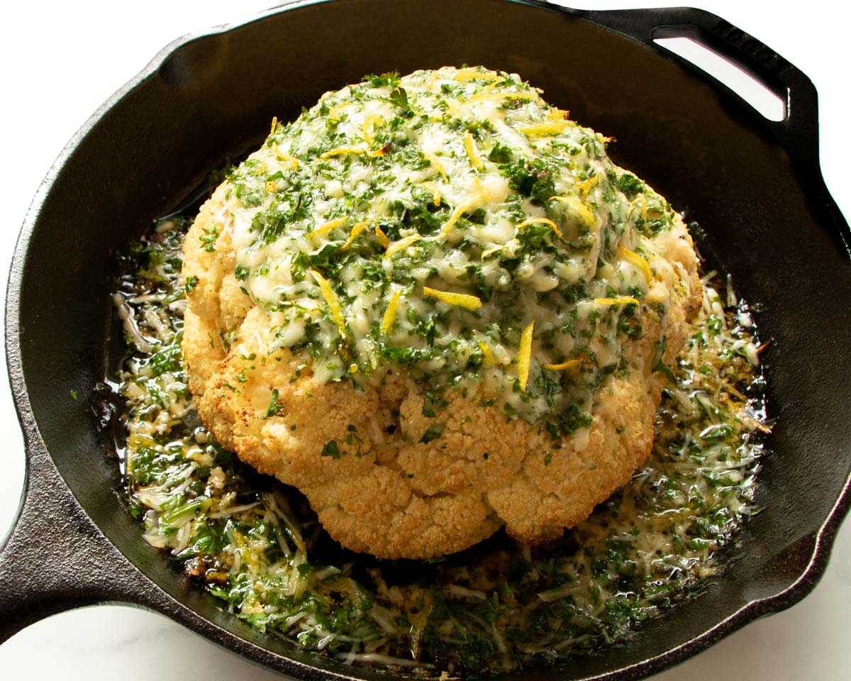 Cauliflower is roasted to a golden crisp, topped with a Parmesan crust, and dressed in a lemon parsley vinaigrette. Served hot in a cast-iron skillet, this vegetarian-friendly dish can be served as a meal, snack or side.