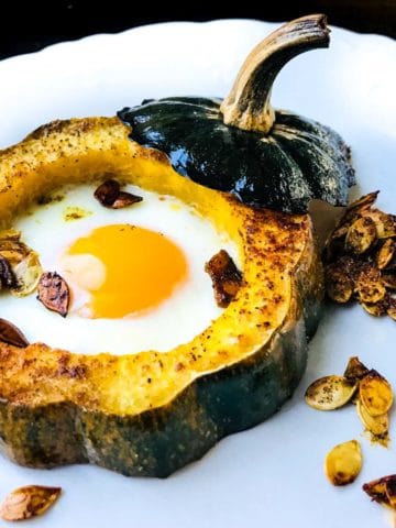 baked acorn squash eggs in a hole on a plate with toasted seeds
