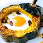 baked acorn squash eggs in a hole on a plate with toasted seeds