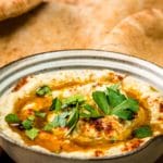 Baba ganoush in a small ceramic bowl garnished with olive oil, paprika and parsley served with mini pita bread