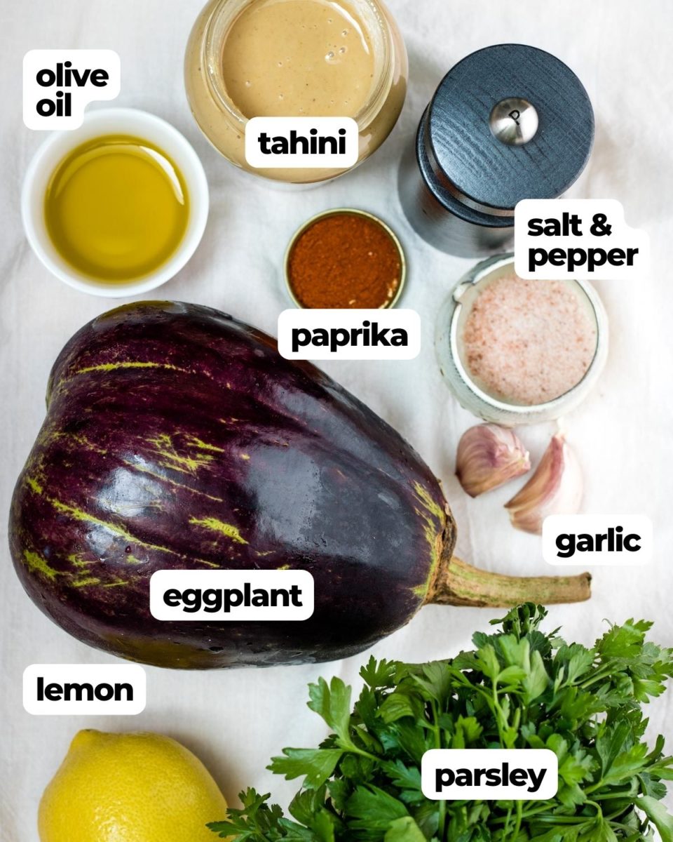 ingredients for baba ganoush clockwise tahini, salt and pepper, garlic, parsley, lemon, eggplant, olive oil and paprika in the center