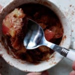 apple mug cake in a tea cup on a saucer being scooped up with a spoon