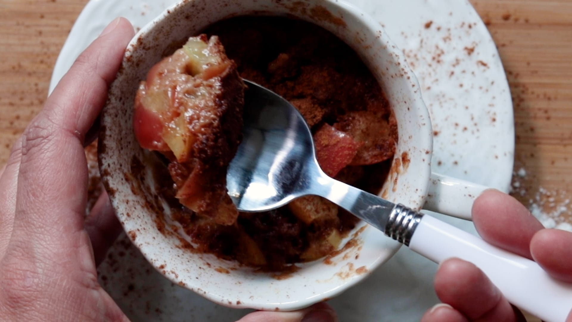 apple mug cake in a tea cup on a saucer being scooped out by spoon