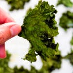 Upclose view of kale chip between fingers