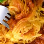 Air fryer spaghetti squash on a plate with pasta sauce and fresh basil