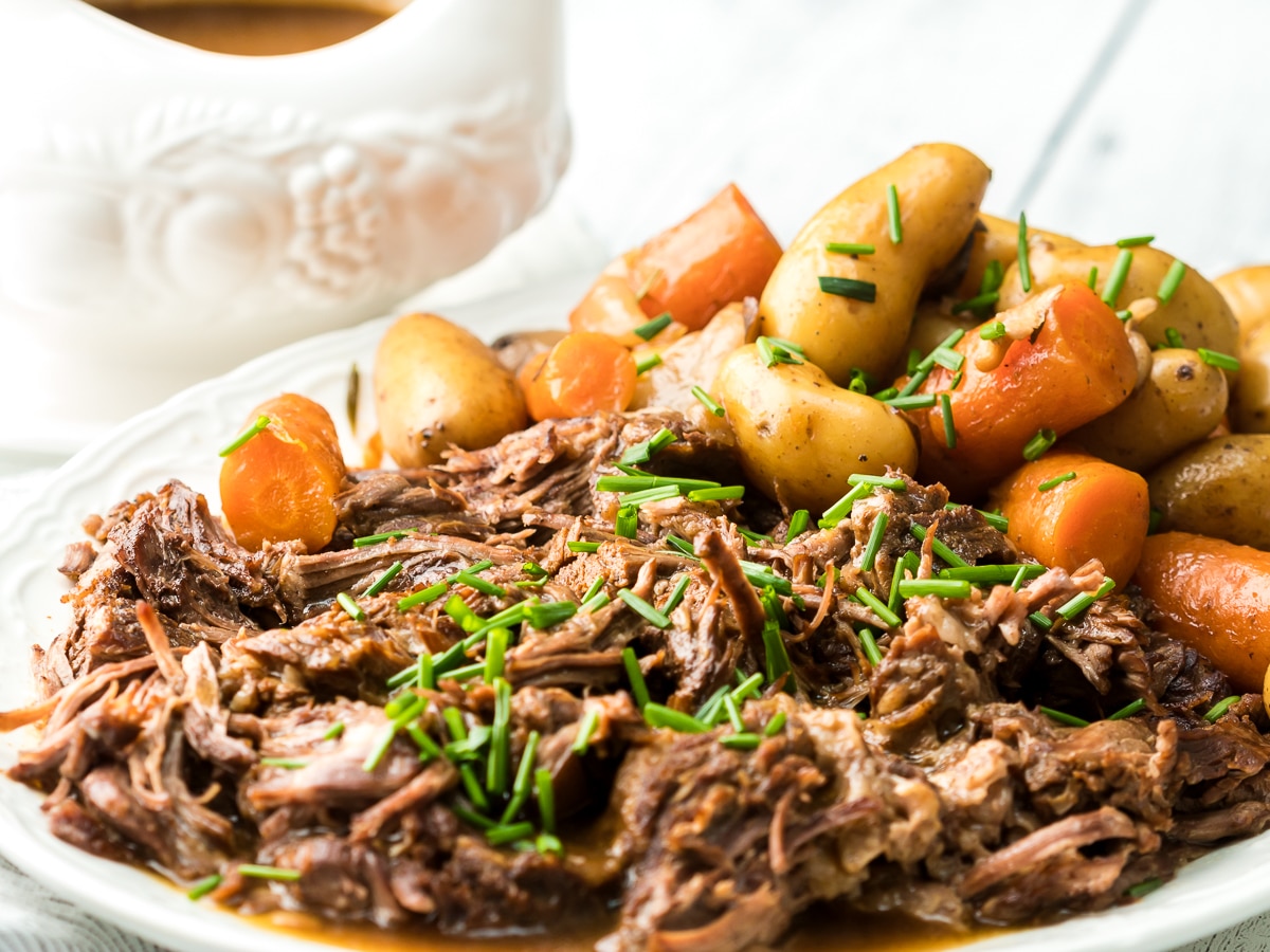 Instant pot pot roast on a platter with gravy too wide shot