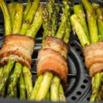 bacon wrapped asparagus bundles in an air fryer basket