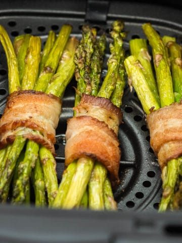 bacon wrapped asparagus bundles in an air fryer basket