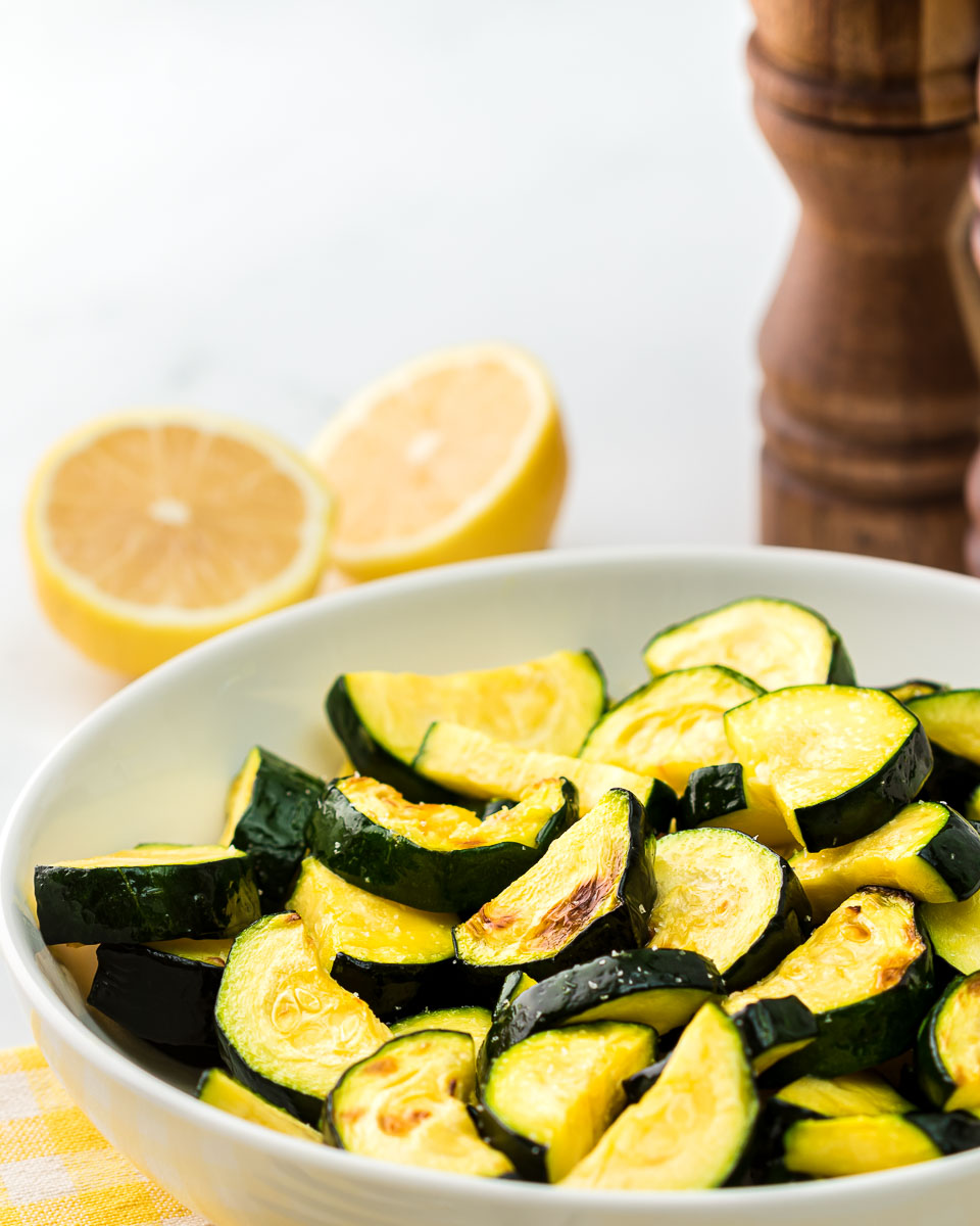 Air fryer zucchini in a bowl with salt and pepper shaker