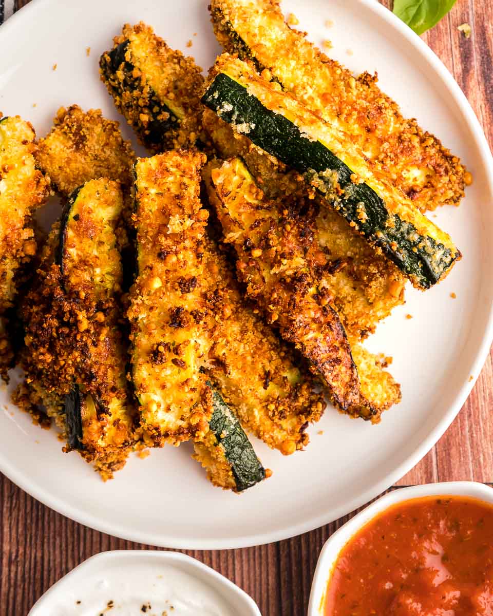 Air fryer zucchini fries on a plate with sauce