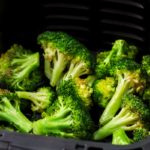 Air fryer broccoli in air fryer basket tall shot