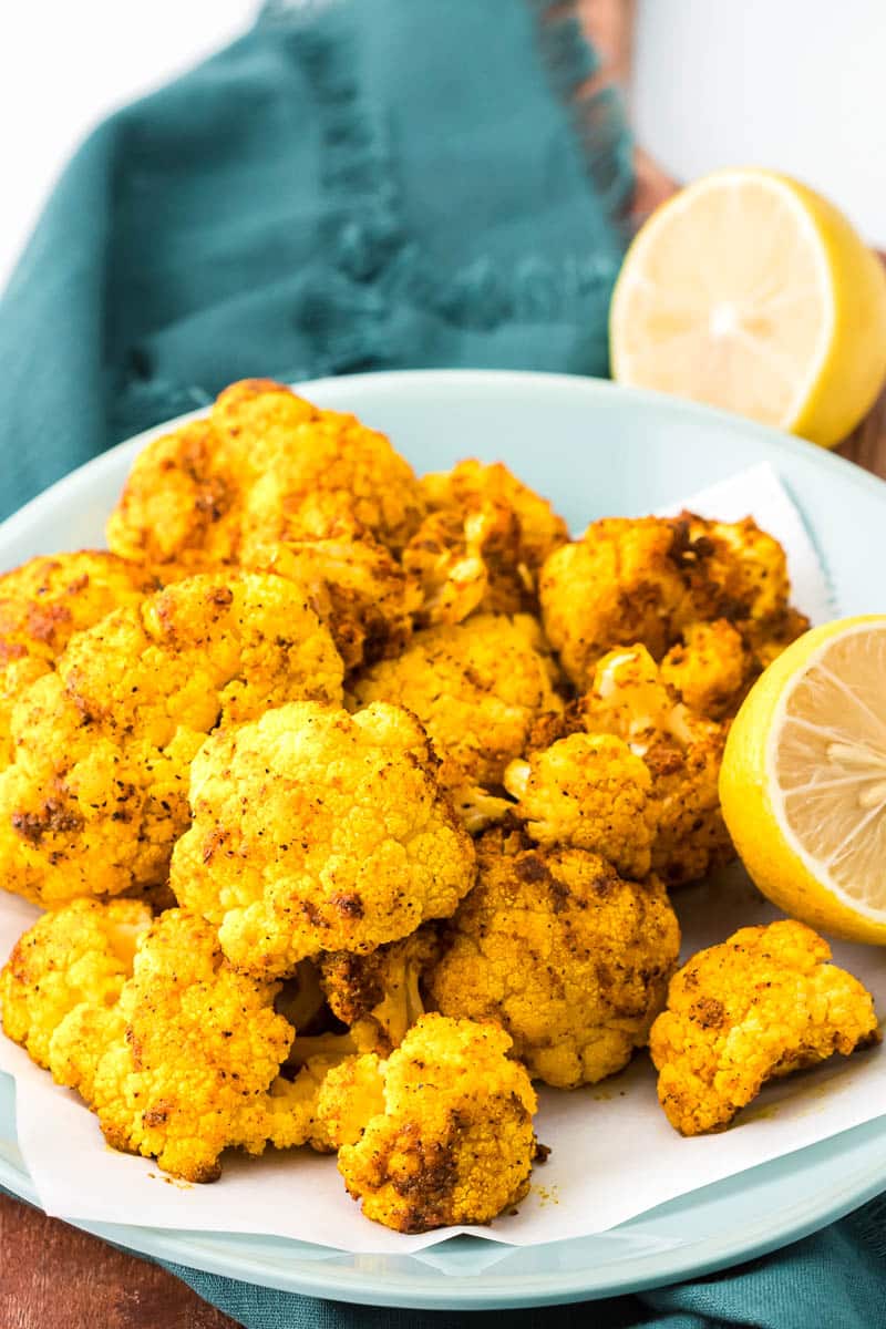 Air fryer cauliflower plated with lemons on a board