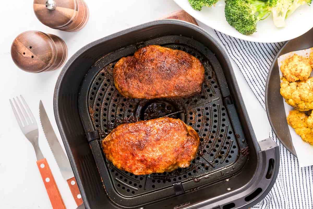 Air fryer pork chops cooked in air fryer basket and served with cauliflower and broccoli