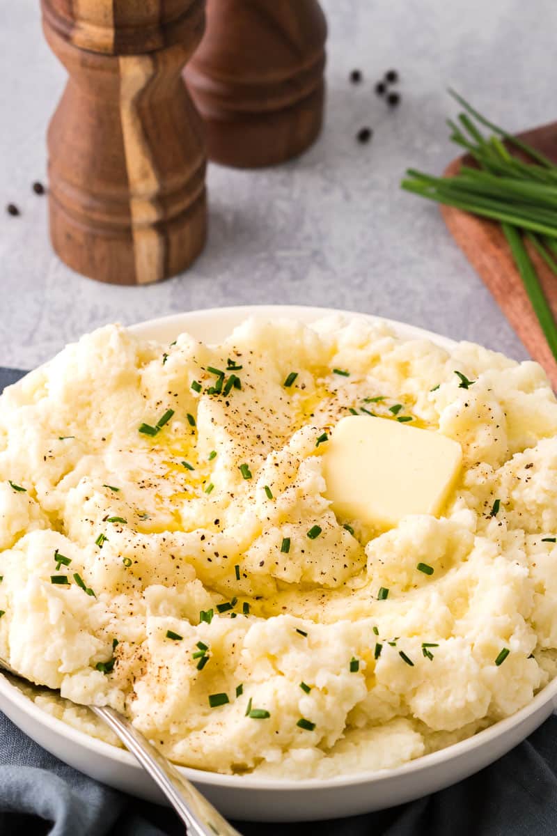 Cauliflower mashed potatoes in bowl with chives and butter