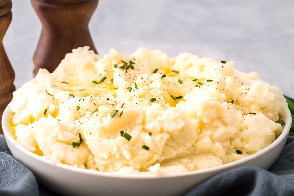 Cauliflower mashed potatoes wide side shot of serving bowl with chives and black pepper
