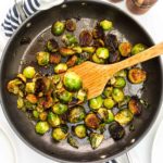 Balsamic glazed Brussels sprouts in a non stick skillet with wooden spatula