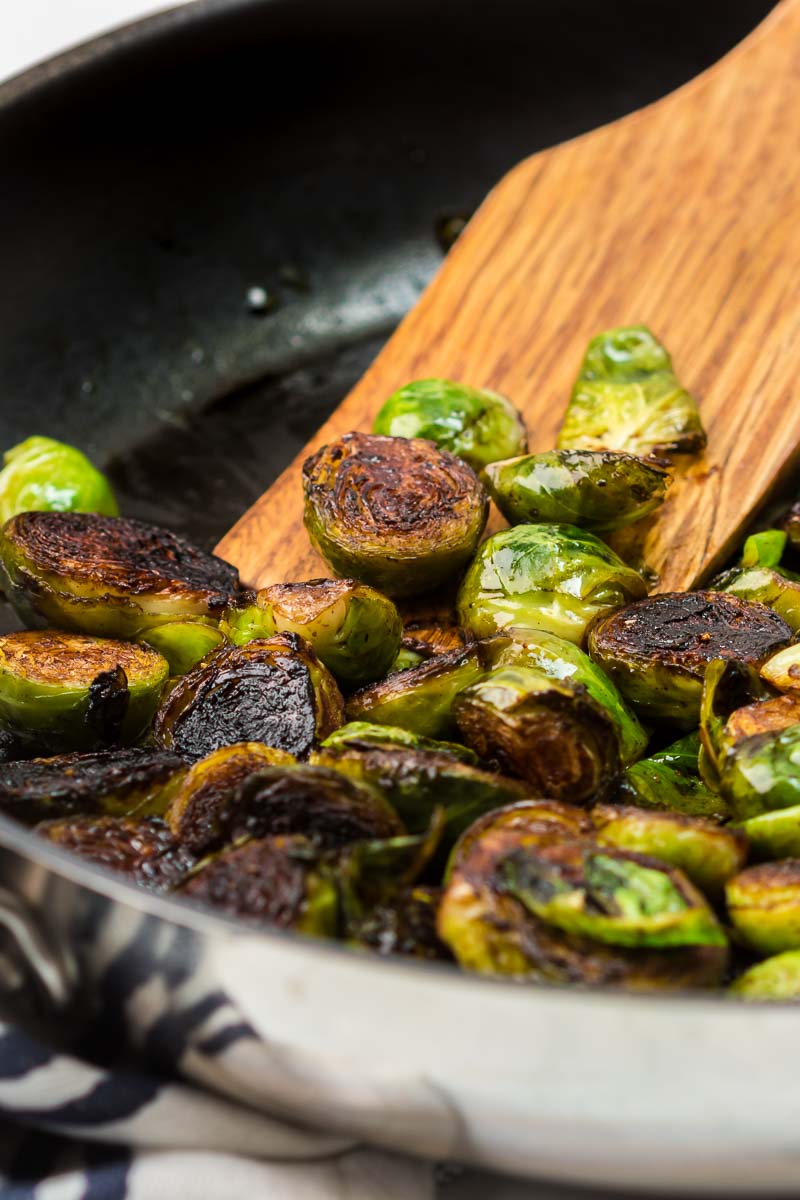 Balsamic glazed Brussels sprouts finished in pan on wooden spatula side view