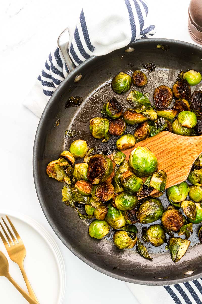 Balsamic glazed Brussels sprouts with plates and in pan overhead view closeup